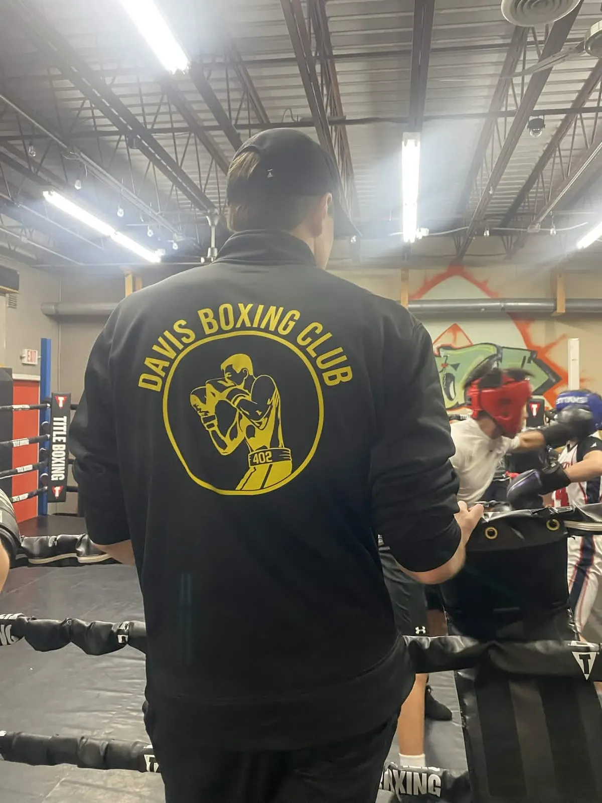 A coach in a Davis Boxing Club jacket at ringside